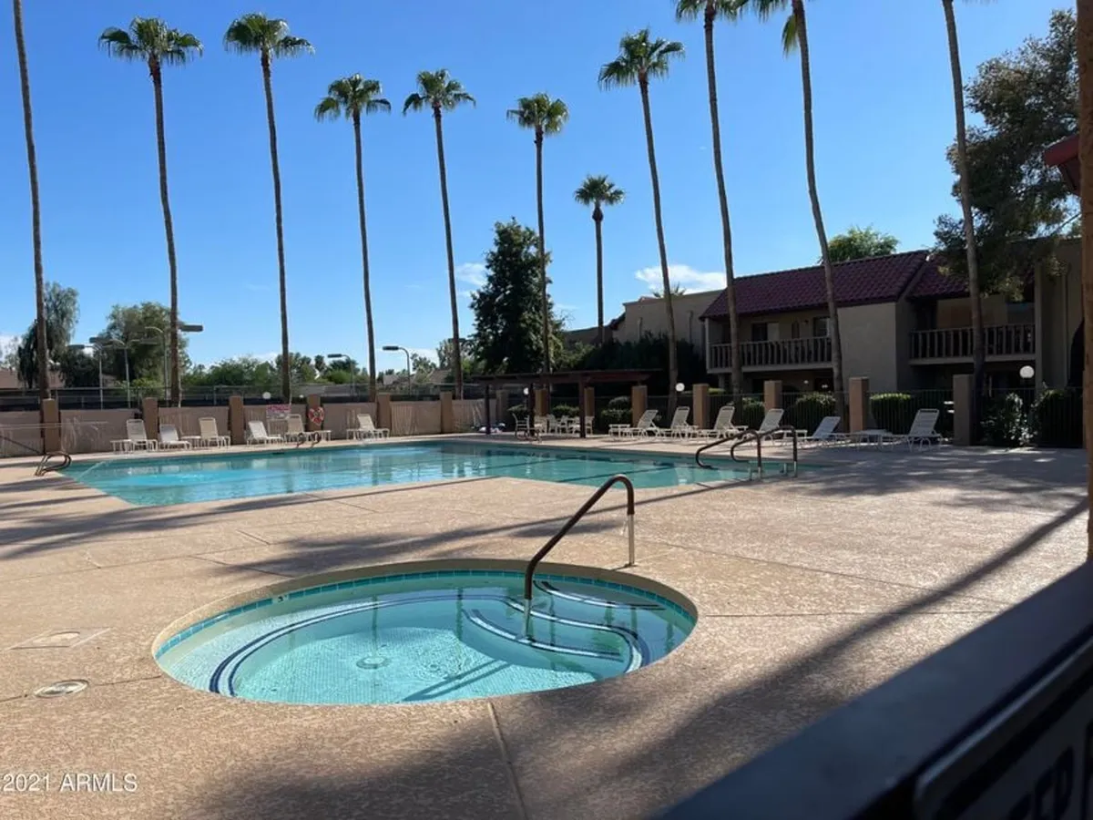 A tranquil swimming pool area with a jacuzzi and lounge chairs, shaded by palm trees. The setting promises relaxation, with space for both quiet time and friendly gatherings, just steps from home.