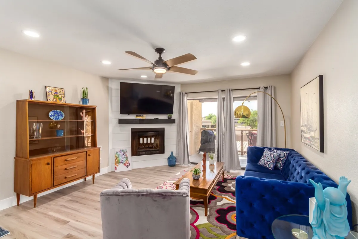 This image showcases a comfortable living area with a blue couch, wooden cabinet, a cozy fireplace, a colorful rug, and a TV. The space is styled for relaxation and socializing, inviting guests to unwind after an active day outdoors.