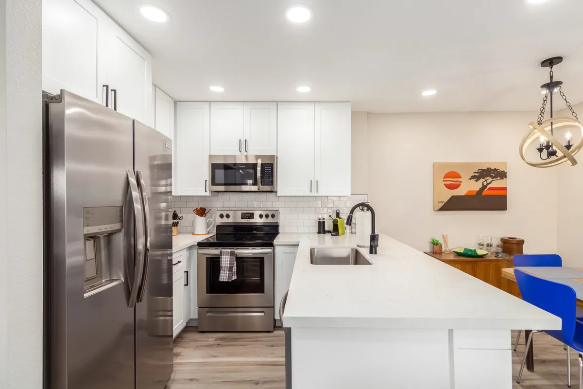 A modern kitchen with stainless steel appliances, a kitchen island with bar seating, and vibrant wall art. The open layout encourages gathering with friends or preparing a post-game meal, connecting indoor comfort with outdoor enjoyment.
